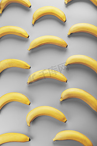 时尚几何色彩摄影照片_2021 年时尚色彩中灰色背景上黄色香蕉的几何图案。