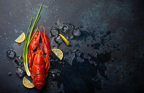 蓝龙虾摄影照片_蓝石背景上带柠檬和冰块的龙虾顶视图