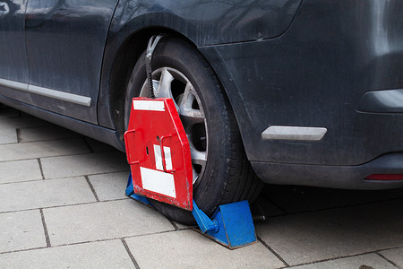 Car wheel clamp Locked illegal parked cars 由于违章停车，车轮被车轮锁挡住了。