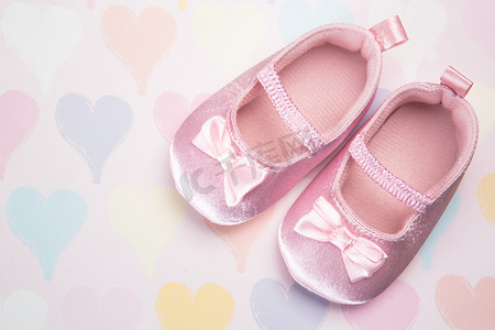 卡通短靴摄影照片_心形图案背景上的婴儿粉色短靴
