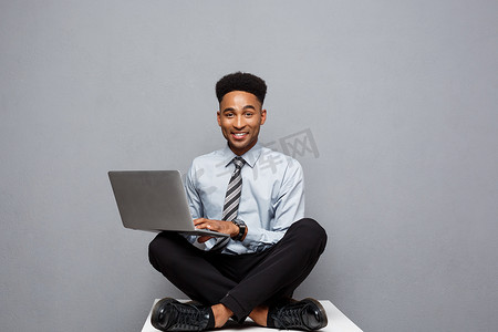 经营理念-快乐英俊的职业非洲裔美国商人喜欢在 labtop 上玩。