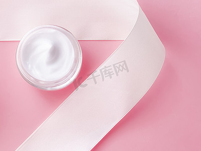 护肤化妆品、面霜保湿罐和粉红色背景的白色丝带、美容产品平铺