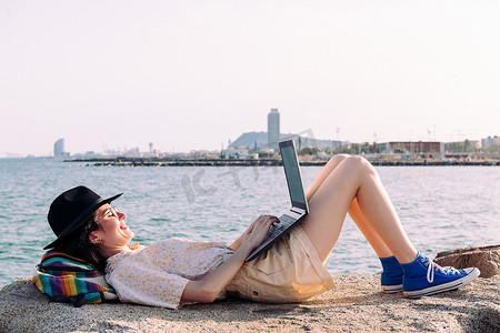 海边躺着用电脑工作的女人