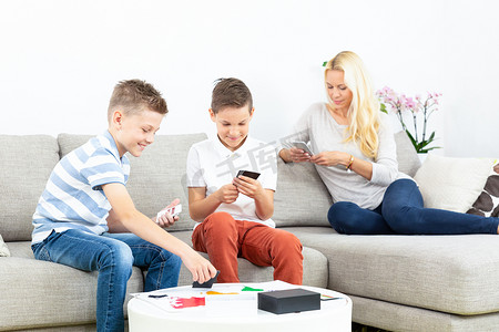 在母亲的监督下，兄弟俩在家里的客厅沙发上玩纸牌游戏。