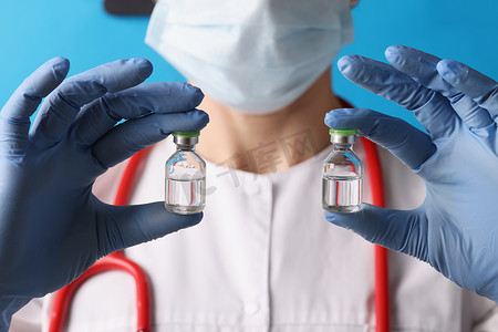 注射液摄影照片_科学家拿着两瓶注射液，戴着蓝色手套