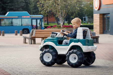 学龄前小男孩驾驶大玩具车，在户外玩得开心。