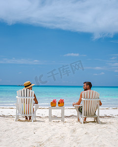 男女喝摄影照片_海滩上的男女情侣喝椰子饮料，普拉兰塞舌尔热带岛屿，海滩和棕榈树，安斯沃尔伯特塞舌尔海滩