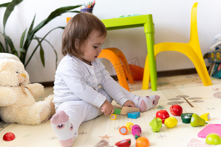 玩具积木摄影照片_快乐有趣的孩子卷发女婴与​​益智玩具积木花。