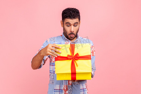 好奇的快乐男人打开礼物的肖像，用爱管闲事的表情偷看盒子里的东西，拆开礼物，期待有趣的生日惊喜。