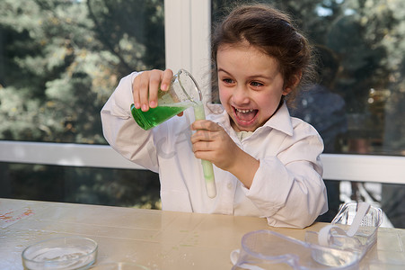 名仁苏打水摄影照片_顽皮的小女孩在学校化学实验室与柠檬酸苏打进行化学反应。