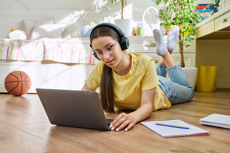 戴眼镜的少女在家使用笔记本电脑学习