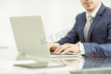 岗位述职报告摄影照片_在工作场所使用笔记本电脑工作的成功商人。