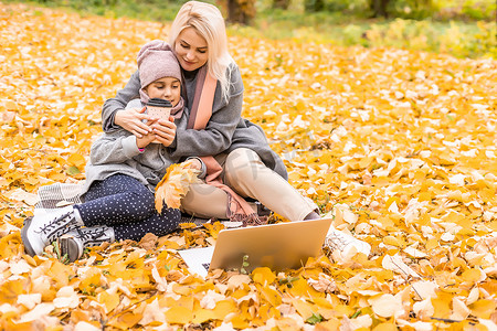 母亲和女儿在秋天的黄色公园。
