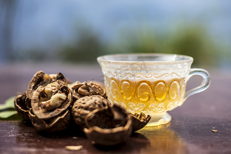 透明玻璃杯中壁坚果或核桃茶的草药有机茶的特写，壳内有生壁坚果，也破碎。