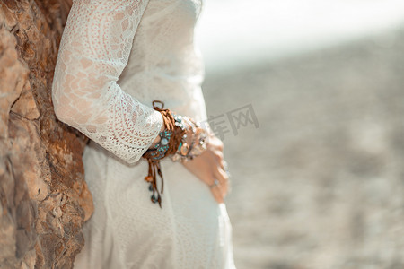 中年妇女金发碧眼，波西米亚风格，脖子和手臂上戴着白色长裙，戴着沙滩装饰。