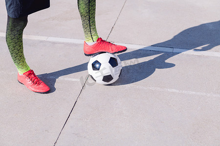 脚踩在水泥地板上的足球上