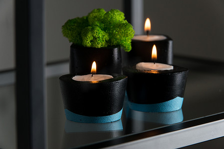 黑色和蓝色混凝土烛台中的蜡烛和苔藓
