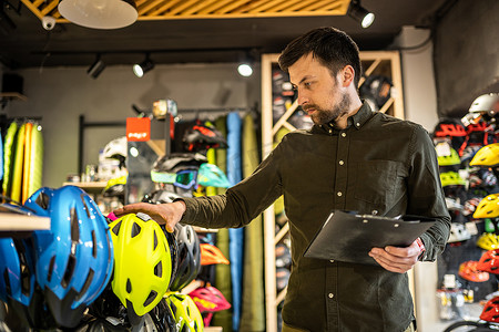 自行车店经理在平板电脑上查看头盔价格信息，卖家在体育用品店盘点。