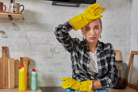 金发女郎戴着防护手套，在家里的厨房里拿着抹布清洁电炉。