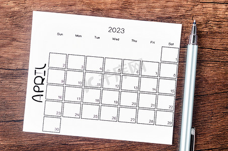 2023 年 4 月的 2023 年月历，木桌上有笔。