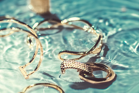 翡翠手镯摄影照片_金手镯、耳环、戒指、翡翠水背景的珠宝、奢华魅力和珠宝品牌广告的假日美容设计