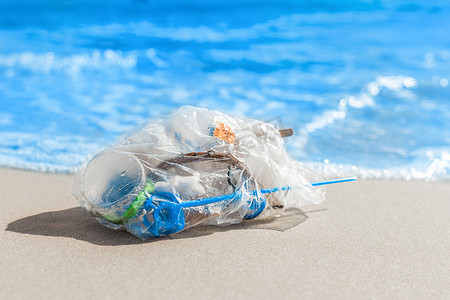 一堆垃圾装在一个包裹里，躺在海边的沙滩上。
