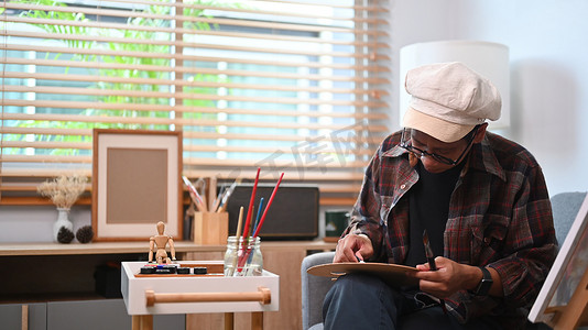 年轻的亚洲男子在他的艺术工作室在画布上绘画。