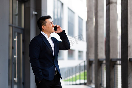 亚洲商人在电话中愉快地微笑着报告好消息