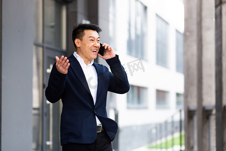 亚洲商人在电话中愉快地微笑着报告好消息