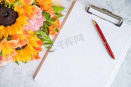 教师节快乐，老板日概念卡和花束。美丽的鲜花花束，带有剪贴板和笔在白色背景。
