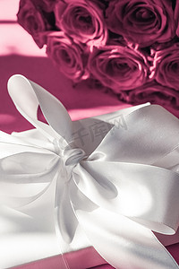 花朵背景摄影照片_豪华假日丝绸礼盒和粉色背景玫瑰花束、浪漫惊喜和鲜花作为生日或情人节礼物