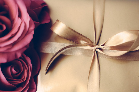 圣诞节礼物棒摄影照片_豪华假日金色礼盒和玫瑰花束作为圣诞节、情人节或生日礼物