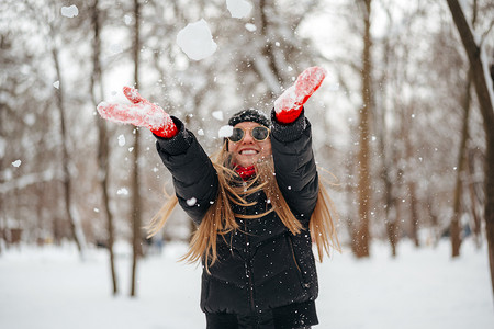 在冬季公园玩雪的快乐微笑的年轻女人
