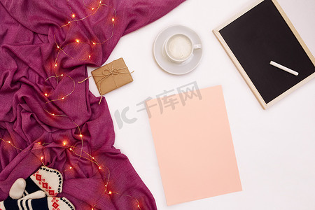 目装饰摄影照片_一杯咖啡、一块黑色小木板和白色粉笔、写有新年目标的粉色纸。