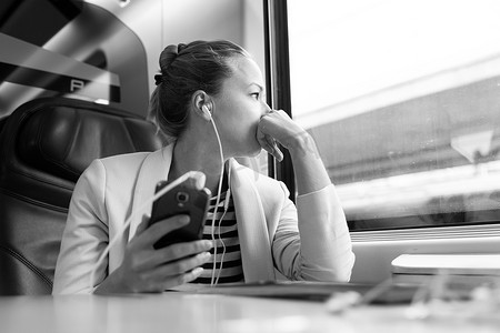 乘火车旅行时，体贴的女商人在手机上收听播客。