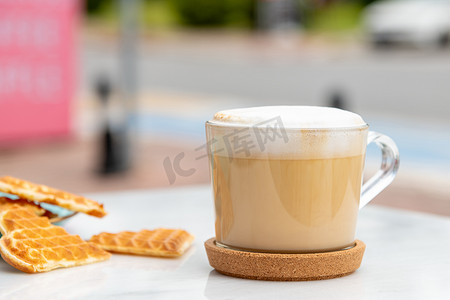玛奇朵摄影照片_咖啡厅花园大理石桌上的拿铁咖啡和心形华夫饼