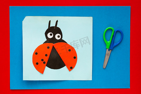 红色贺卡摄影照片_多色床单背景下儿童用纸制成的瓢虫