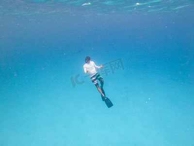 自由潜摄影照片_蓝色海洋中男子自由潜水的水下视图。