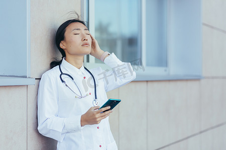 悲伤的亚洲医生护士，在休息时在诊所附近使用电话，女人严重头痛