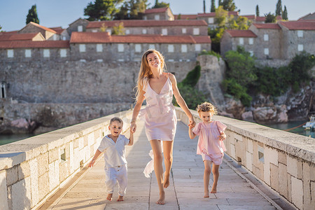 母亲和两个孩子的女儿和儿子游客以美丽的景色为背景，圣斯蒂芬岛，圣斯蒂芬岛，位于黑山布德瓦的布德瓦里维埃拉。