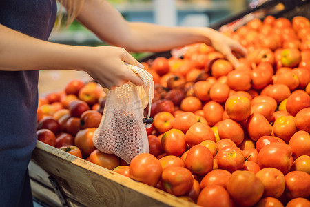 蔬菜超市摄影照片_一位女士在超市挑选西红柿时没有使用塑料袋。