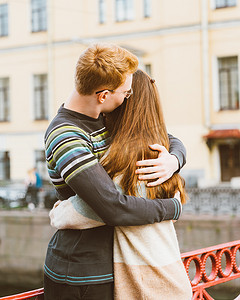 红头发的男人亲吻了一个女人的头顶，一个穿着毛衣的男孩安慰着一个长着深色浓密头发的女孩
