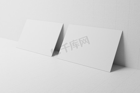白色名片纸模型靠在墙壁模板上，带有空白空间盖，用于在纸板背景上插入公司徽标或个人身份。