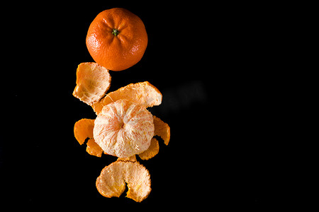 黑色背景中柑橘类植物柑橘的成熟果实，去皮，也不去皮