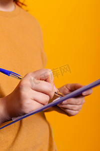 握铅笔摄影照片_手握笔和写在剪贴板纸上的特写
