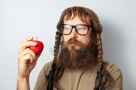 留着辫子的沉思科学家手里拿着苹果，目光若有所思地移开。