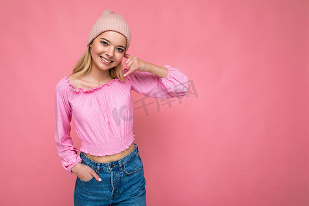 迷人的微笑快乐的年轻金发女性孤立地站在色彩缤纷的背景墙上，穿着日常时尚的服装，看着相机表现出面部情绪