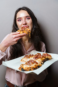 女孩快递员在灰色背景下吃 Pinsa 罗马披萨美食意大利美食。