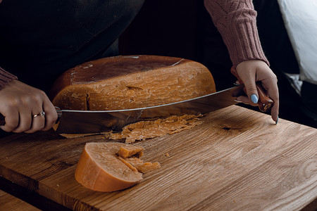 刀语摄影照片_使用干酪荷兰刀将陈年干酪帕尔马干酪与晶体切片。