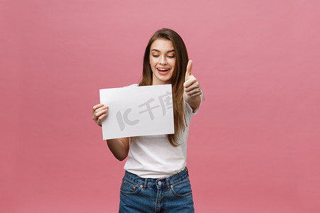 女孩卡片摄影照片_年轻美女拿着空白卡，在粉红色背景中竖起大拇指